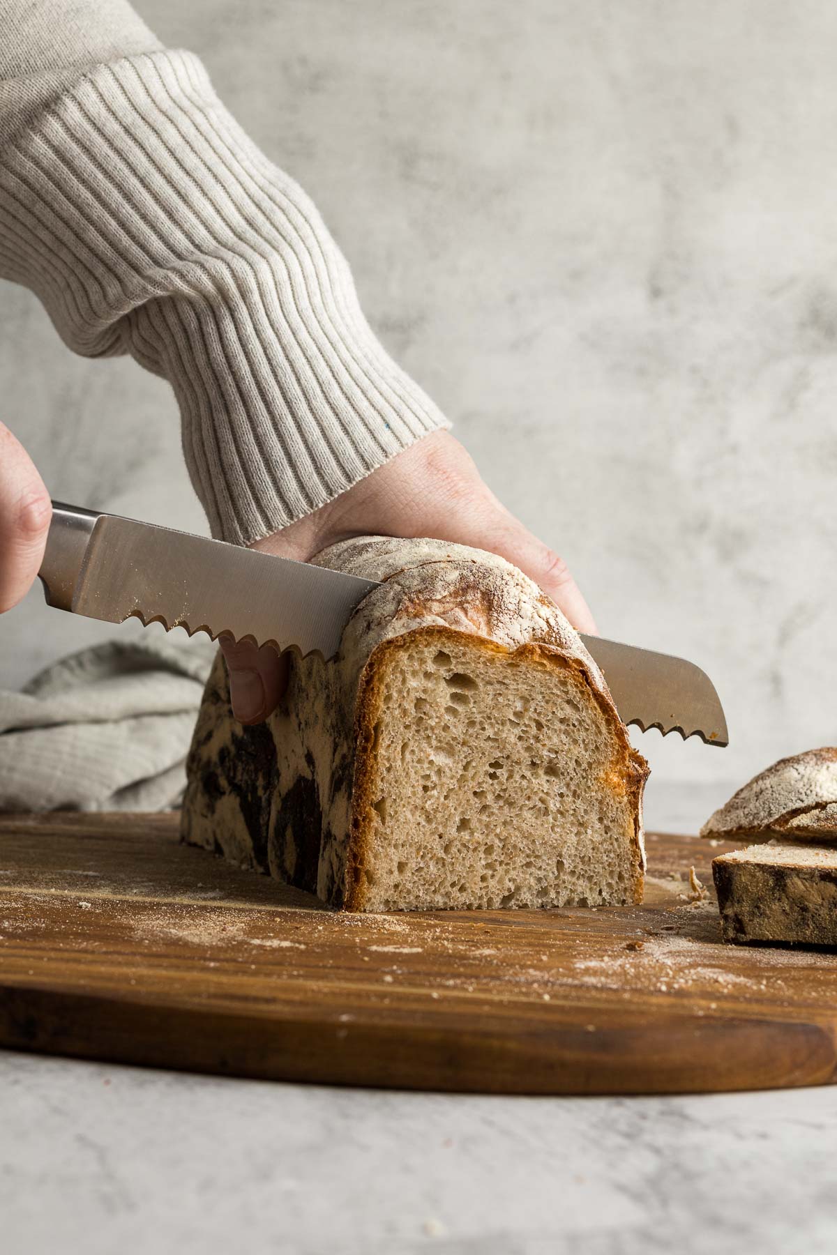 Hand slicing the country loaf with a bread knife.