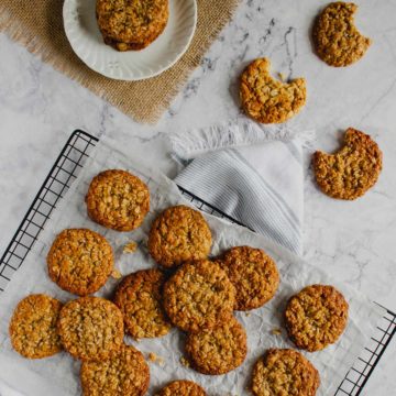 Anzac Biscuits on a tray with 3 cookies on the side with bites out of them.