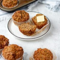 Bran muffins on a plate, sliced with a pat of butter.