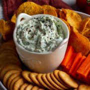 Spinach and Feta Dip surrounded by crackers, chips and carrots.