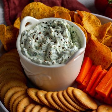 Spinach and Feta Dip surrounded by crackers, chips and carrots