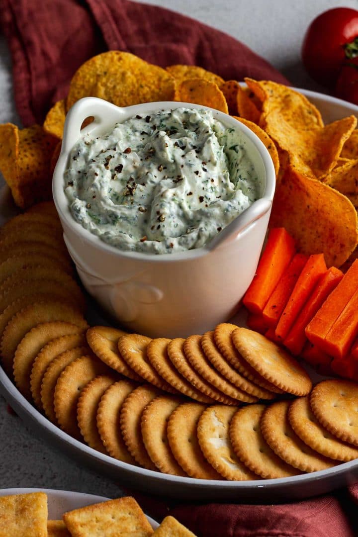 Spinach and Feta Dip surrounded by crackers, chips and carrot