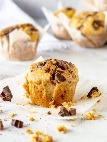 Chocolate chip muffin surrounded by chunks of chocolate.