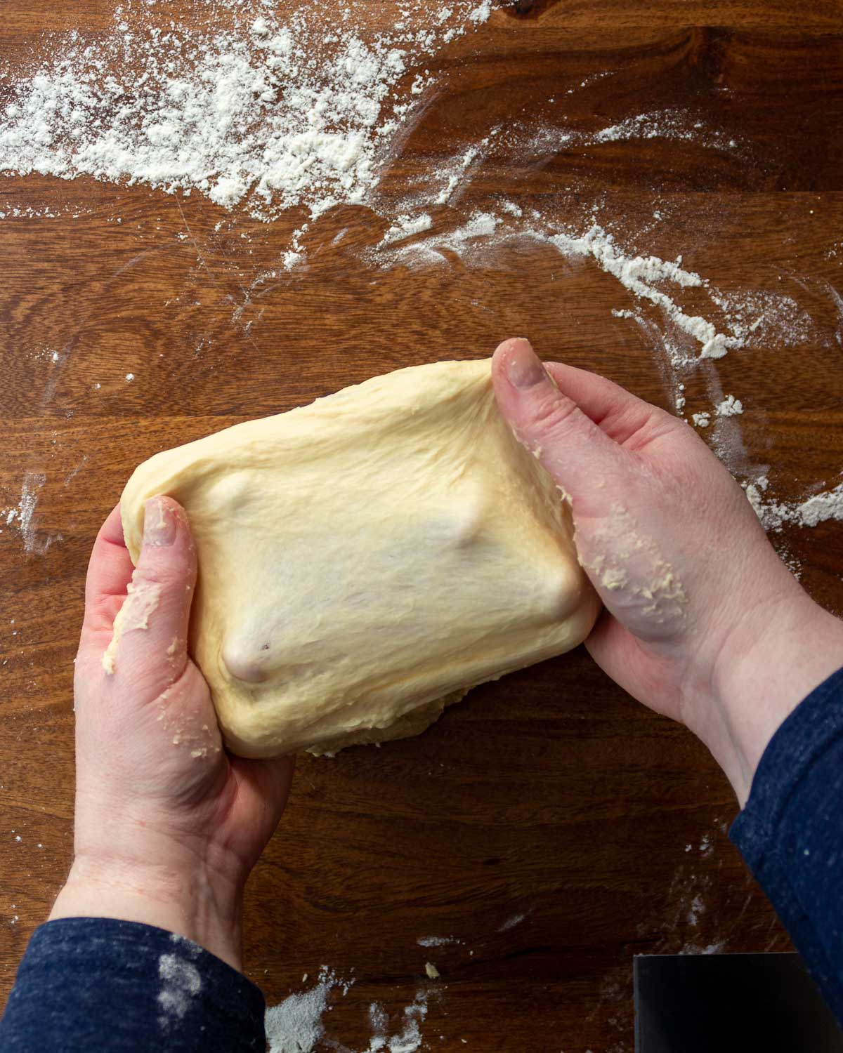 Step 3 - Hand stretching out a piece of dough to show the window pane test.