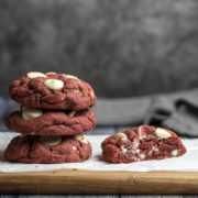 Stacked red velvet cookies next to a cookie sliced in half.
