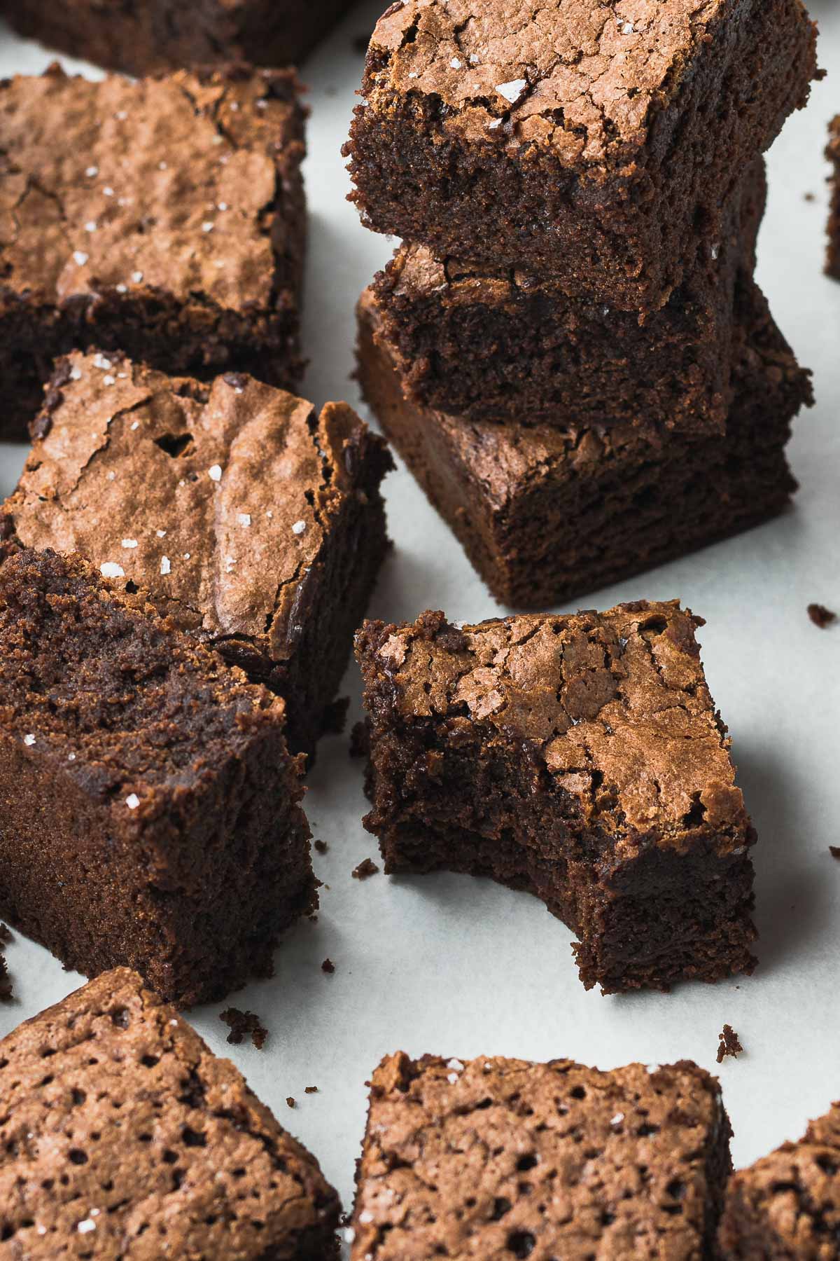 Chocolate brownies spread out on baking parchment
