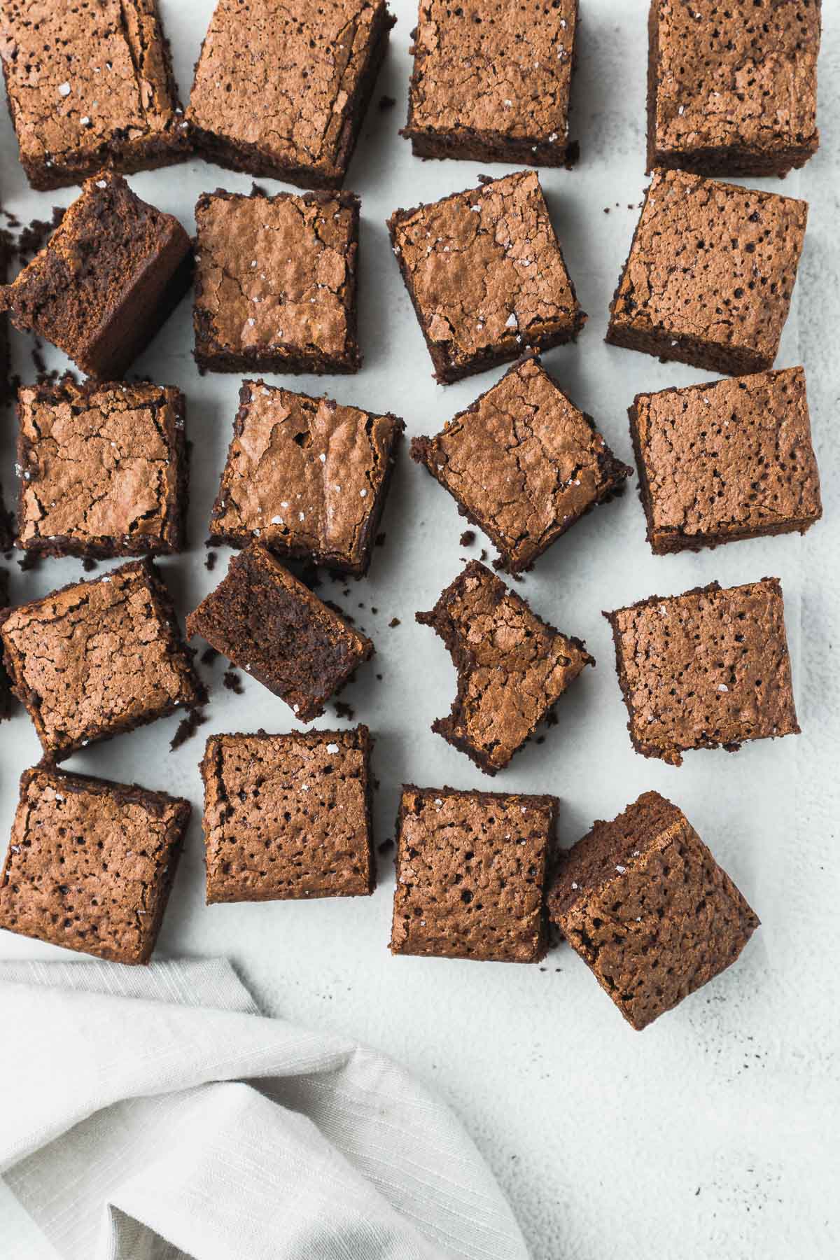 Brownies sliced and placed on parchment paper with two brownies on their sides to show the chewy centers