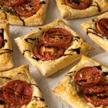 Close up of tomato, onion and ricotta tartlets drizzled with a balsamic glaze.