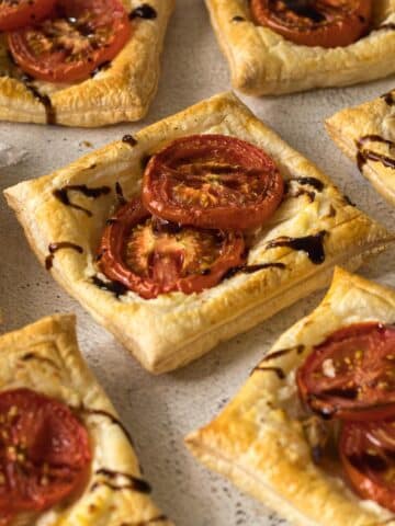 Close up of tomato, onion and ricotta tartlets drizzled with a balsamic glaze.