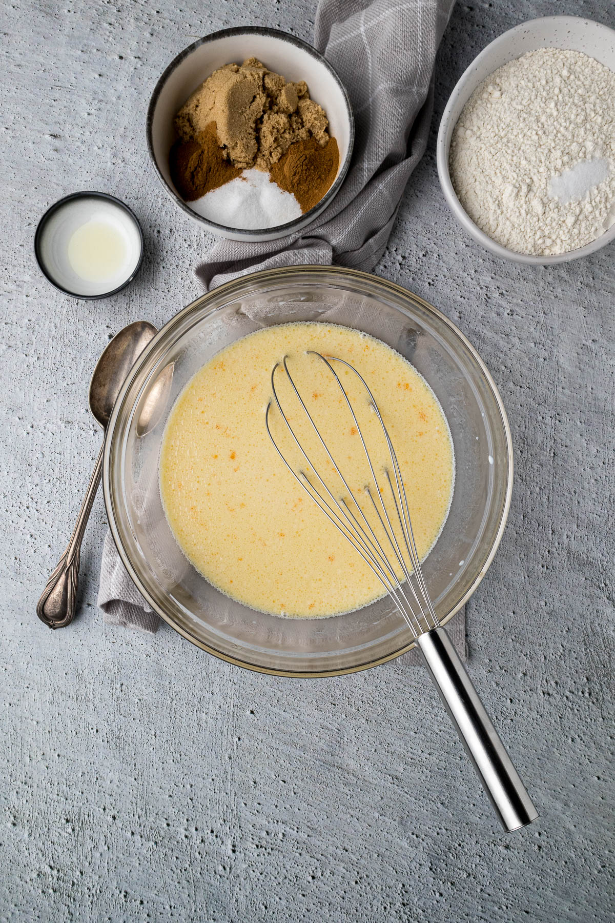 Eggs, milk, and oil whisked together in a large mixing bowl.