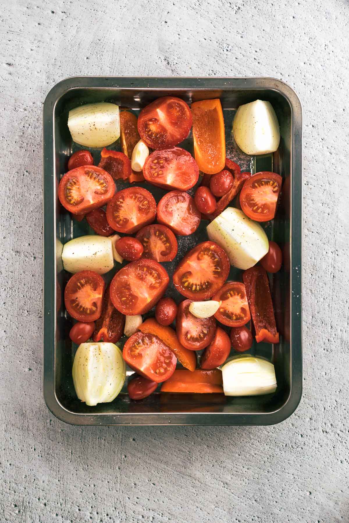 Vegetables in a roasting dish with olive oil, salt and pepper.