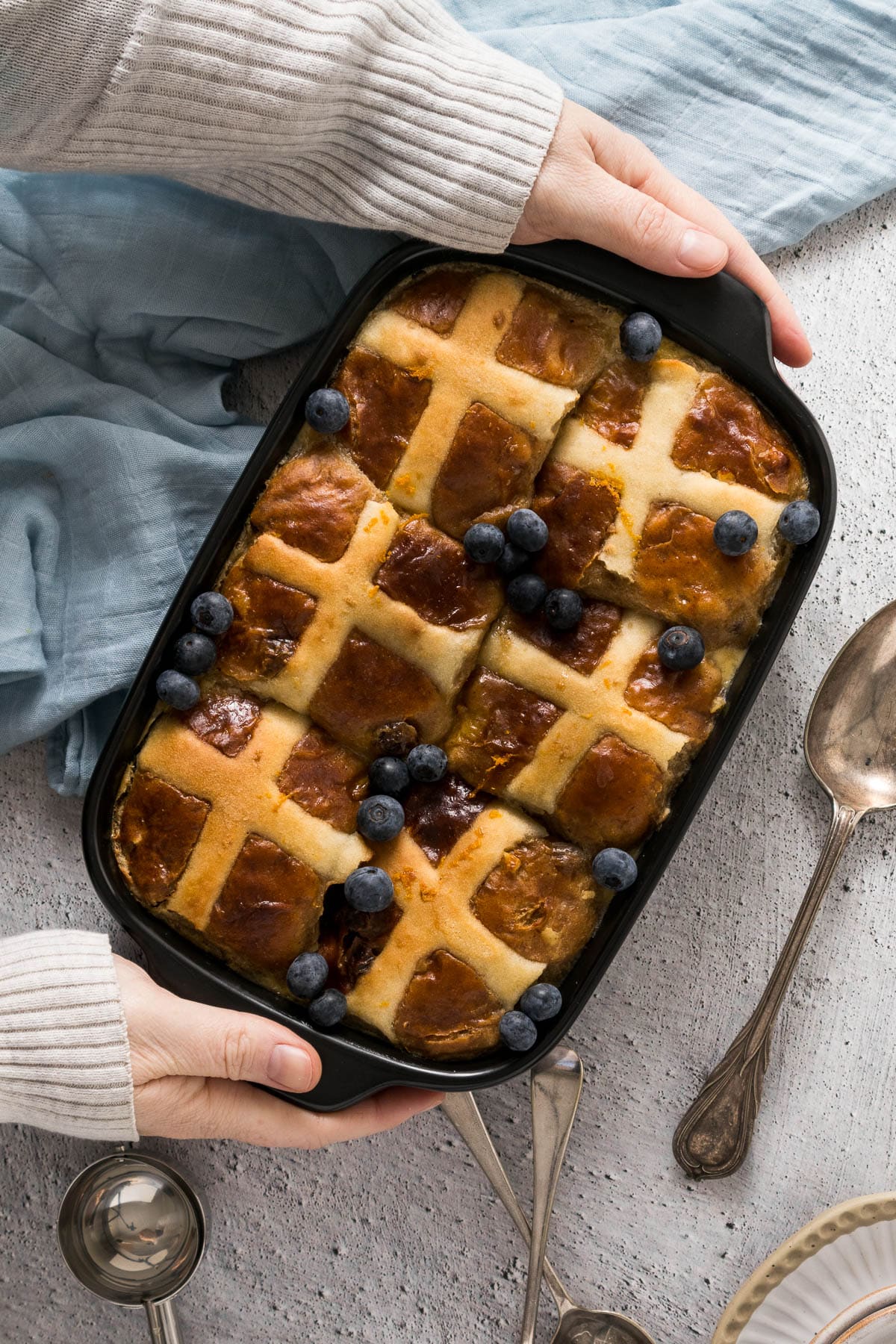Top down view of hands placing the hot cross bun pudding on the counter.