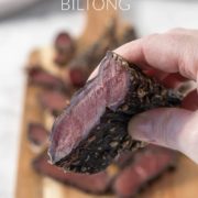 Hand holding a piece of sliced biltong.