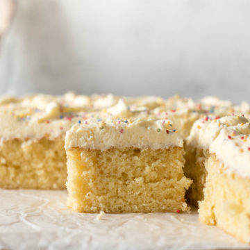 Sliced vanilla traybake showing vanilla buttercream frosting and sprinkles.