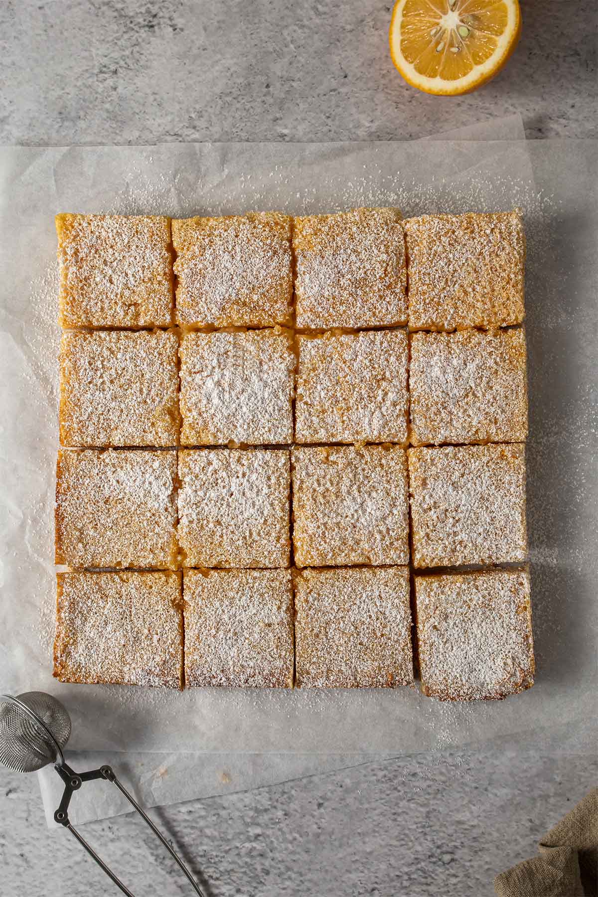 Sliced lemon slice on parchment paper dusted with icing sugar.