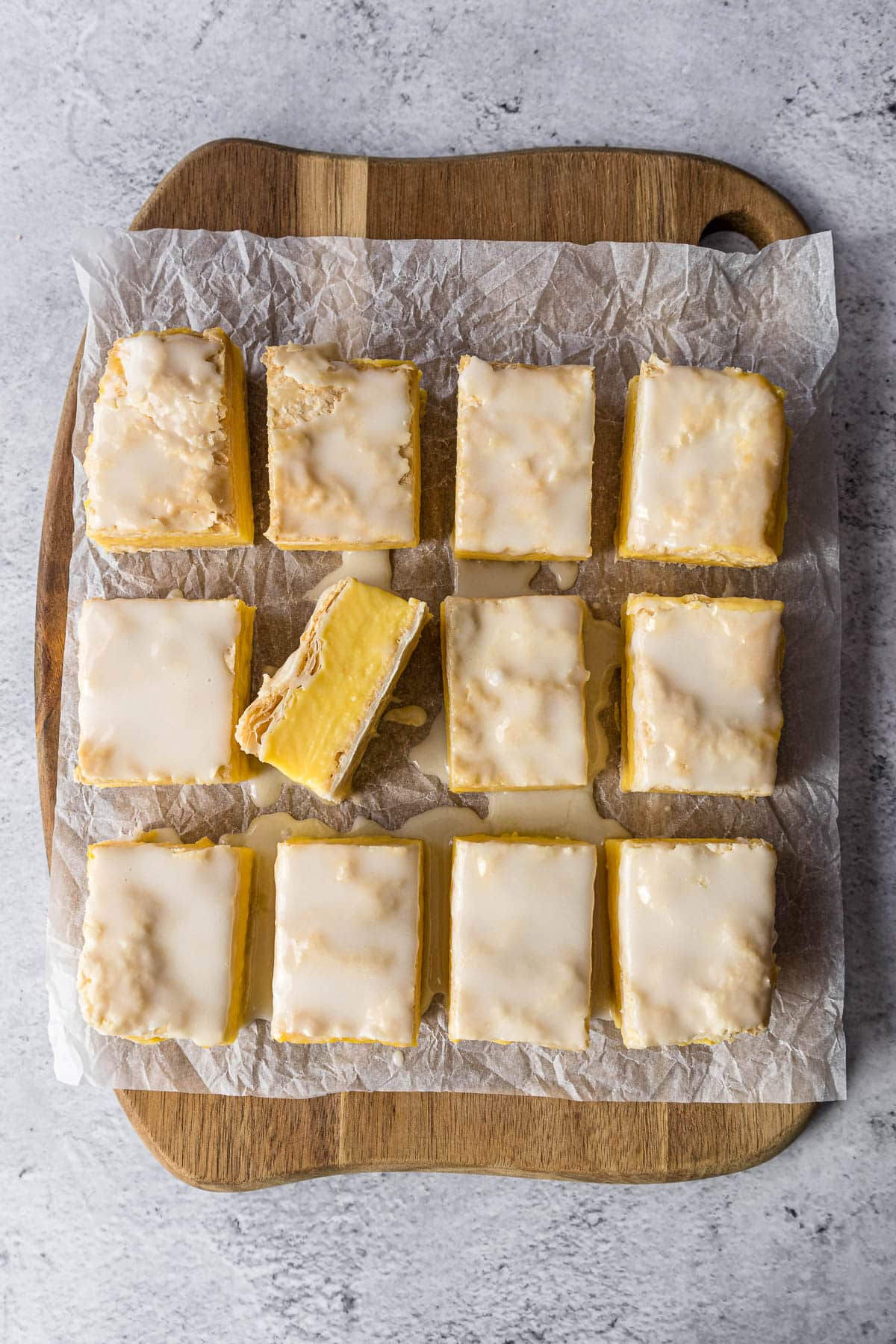 Sliced custard slice topped with glaze on a chopping board.