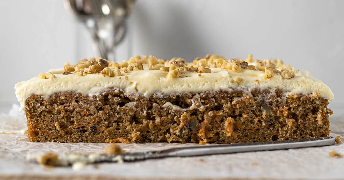 Sliced carrot cake tray bake with cream cheese frosting.