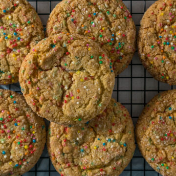Sugar cookies with sprinkles on a cooling rack.