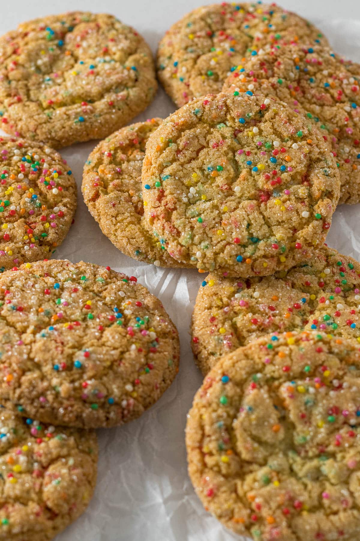 Sugar cookies with sprinkles on parchment paper.