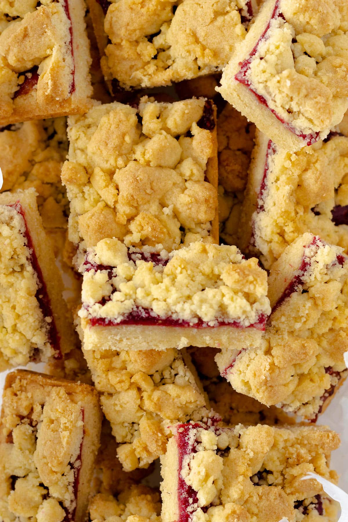 Jam squares in a biscuit tin lined with parchment paper.