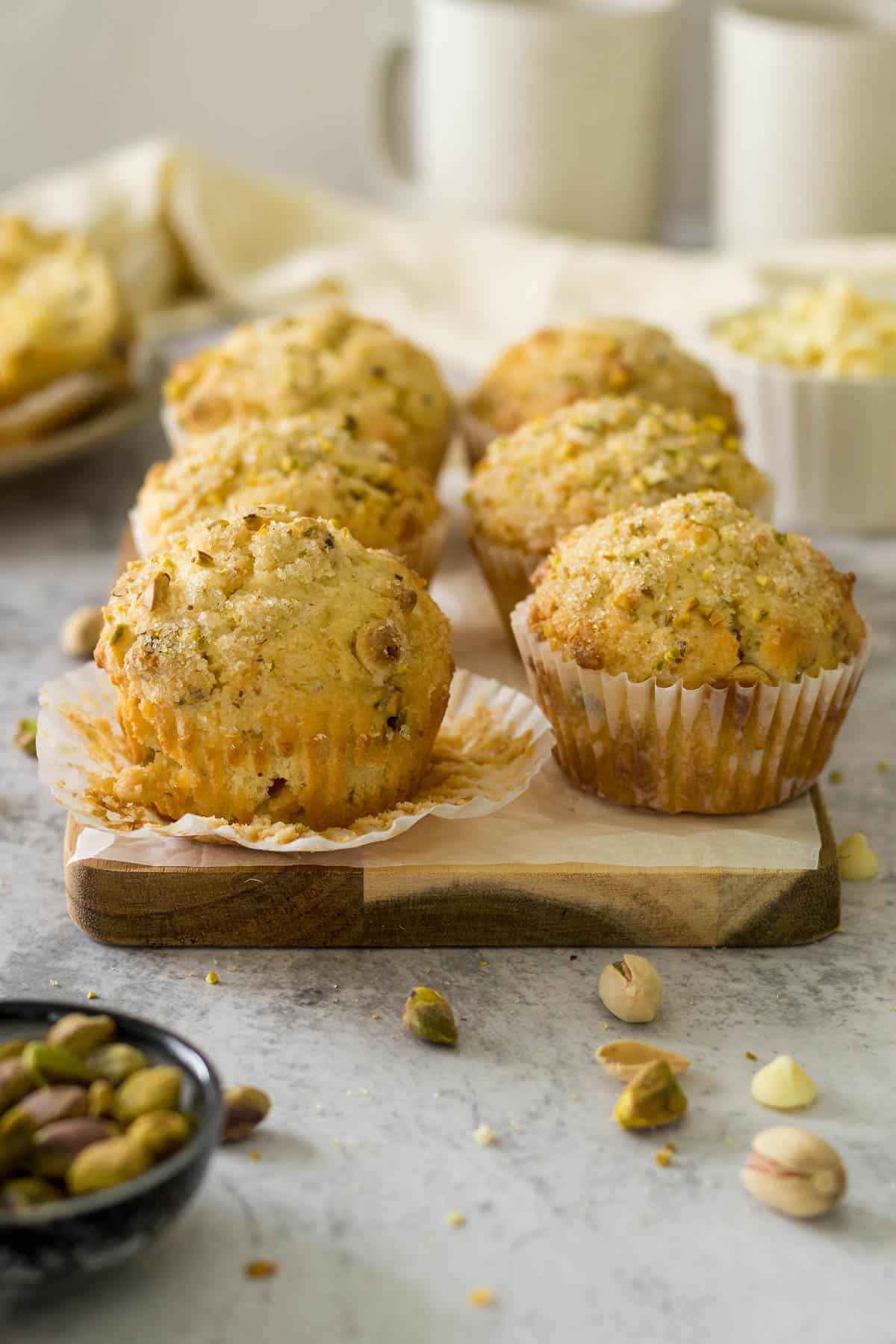 Pistacho muffins on a wooden serving board.