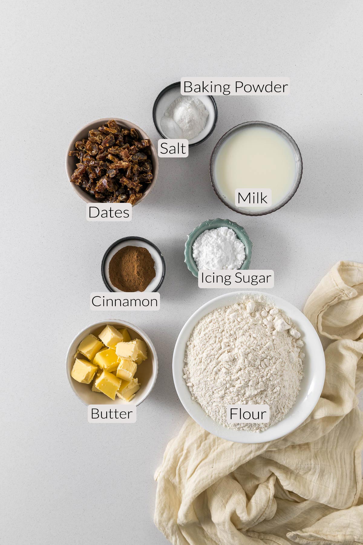 Date scone ingredients - flour, butter, milk, dates, cinnamon, icing sugar, baking powder, and salt.