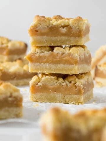 Three tan squares stacked on each other showing the layers of shortbread and caramel.