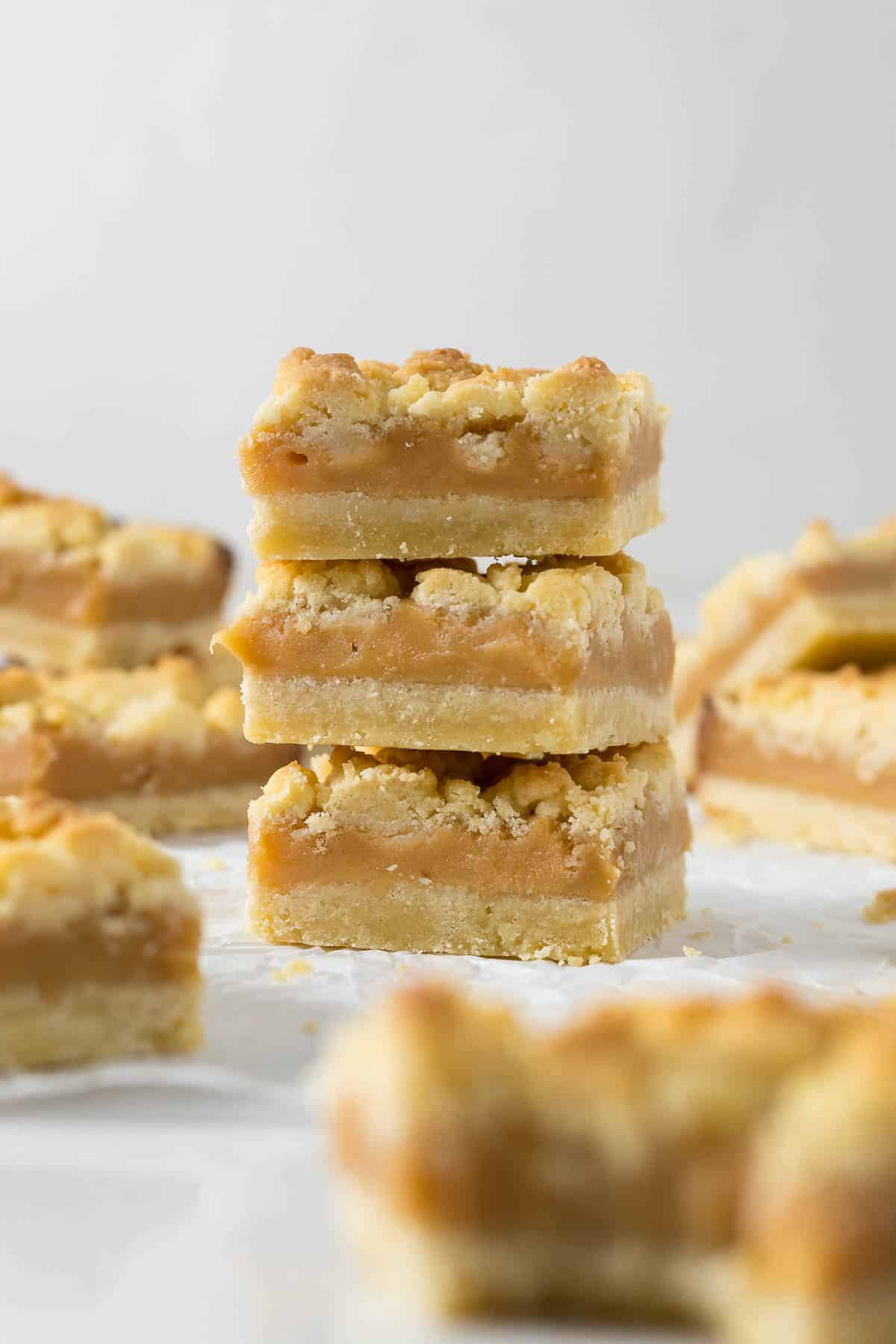 Three tan squares stacked on each other to show the layers of shortbread and caramel.