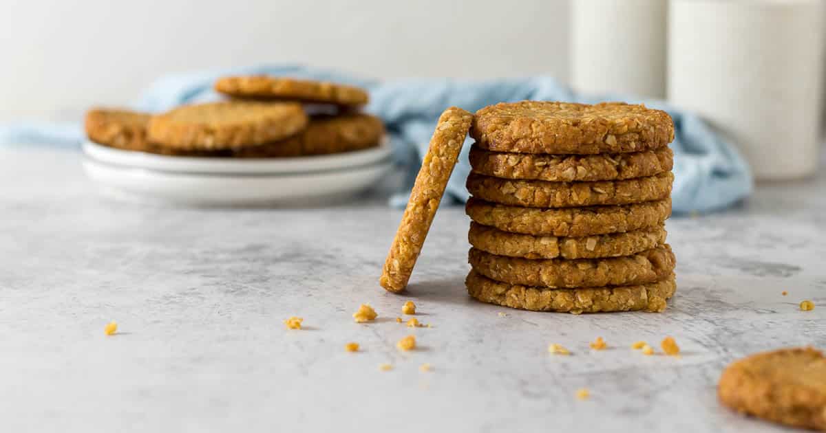 Stack of ANZAC biscuits with one propped on the side of the stack to show the side view.