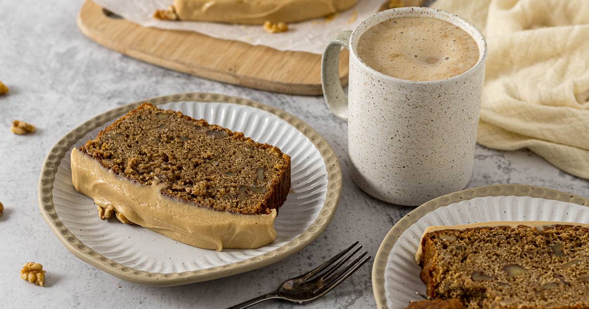 Coffee walnut loaf cake on a plate with a cup of coffee.