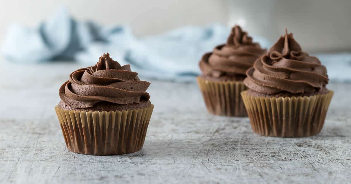 Three chocolate cupcakes with a chocolate buttercream swirl.