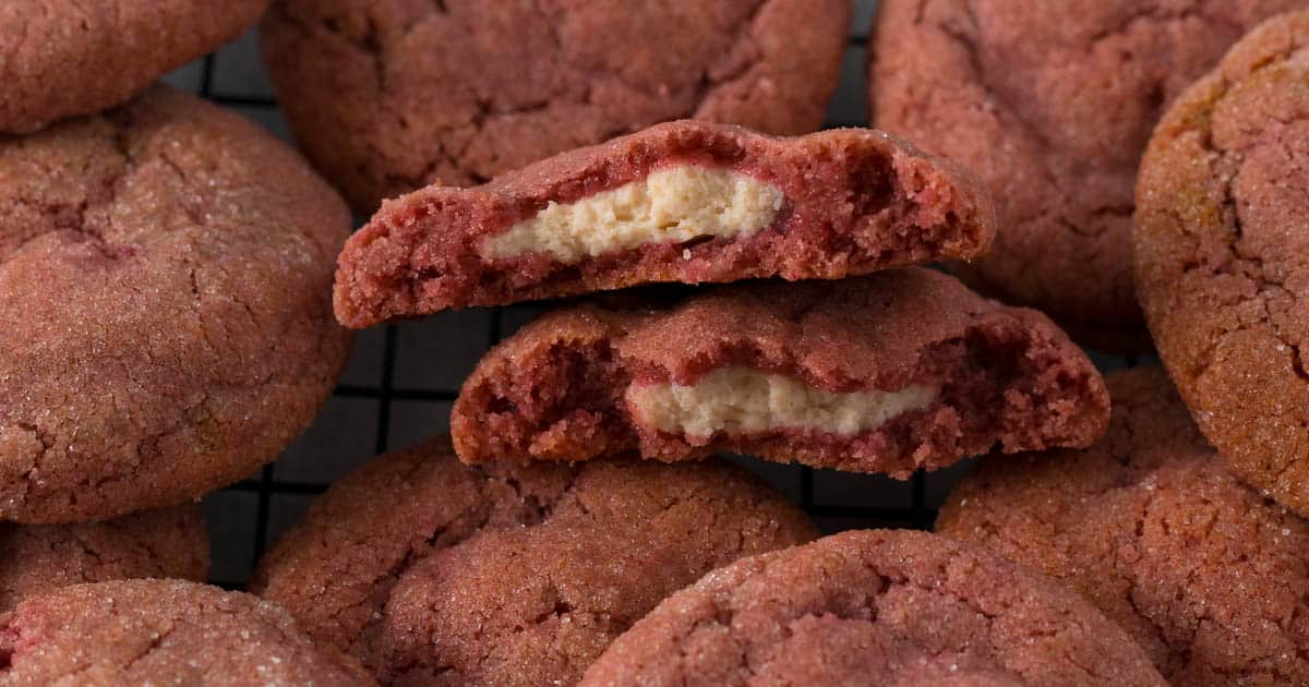 Close up of a strawberry cheesecake cookie split in two to show cream cheese filling.