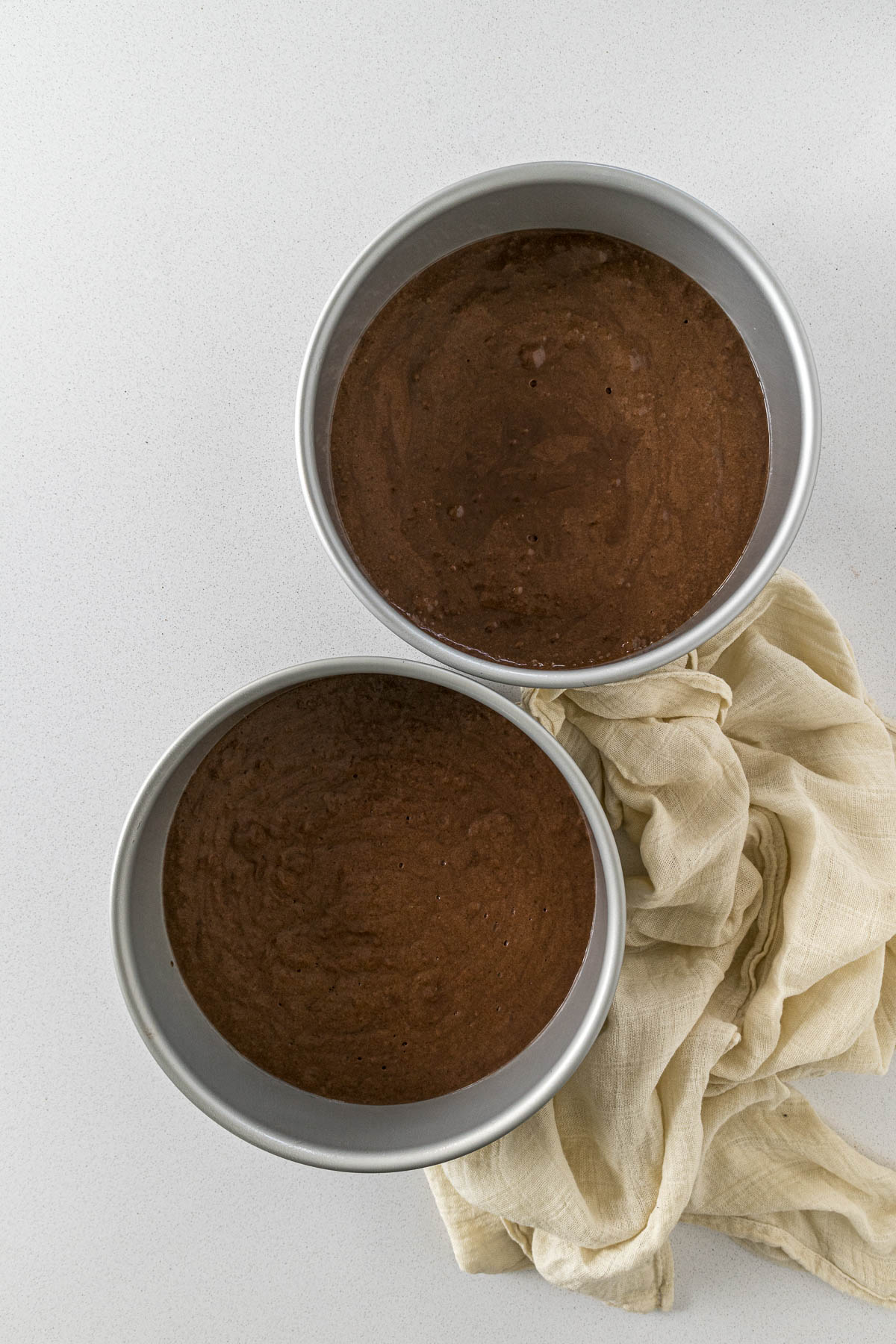 Chocolate cake batter divided between two cake pans.