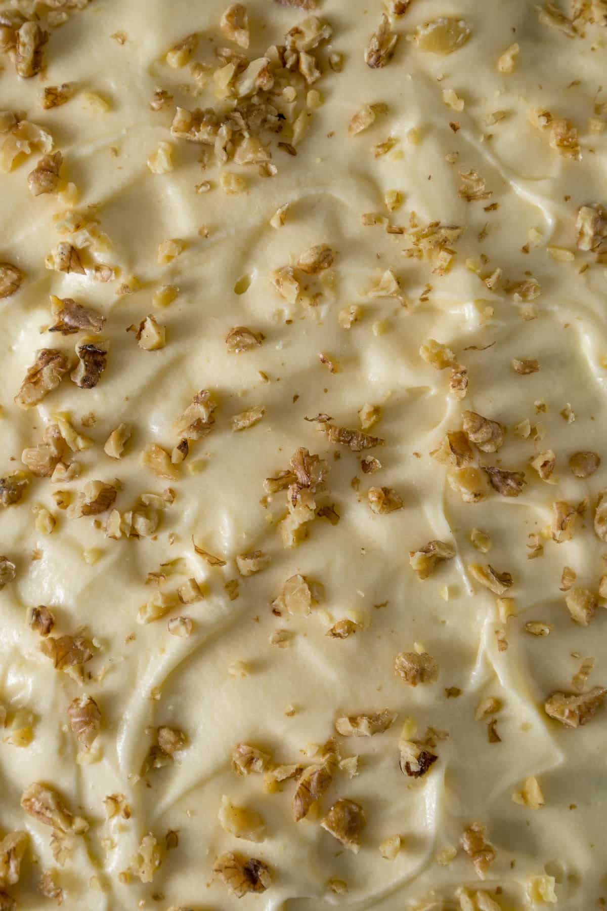 Cream cheese frosting sprinkled with walnut pieces.