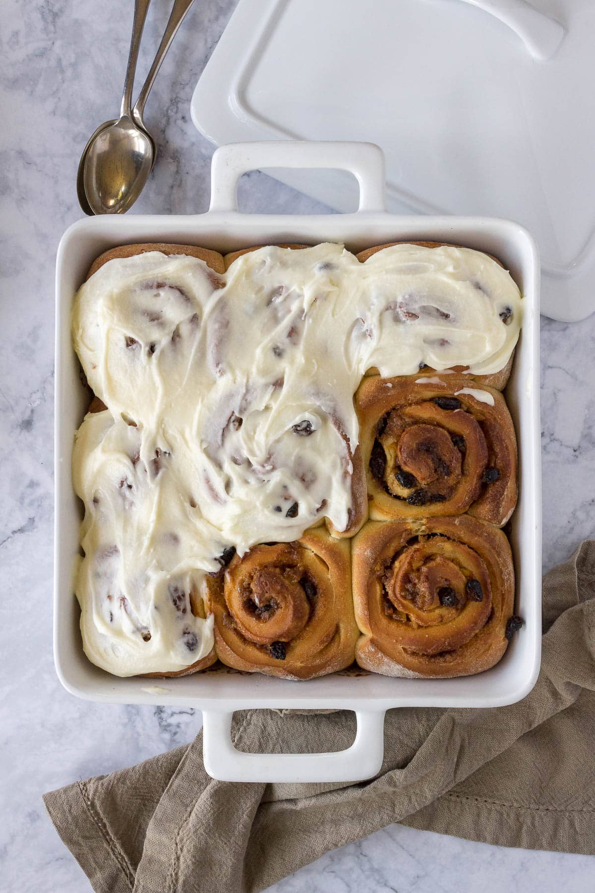 Half-frosted Chelsea buns in a baking dish.
