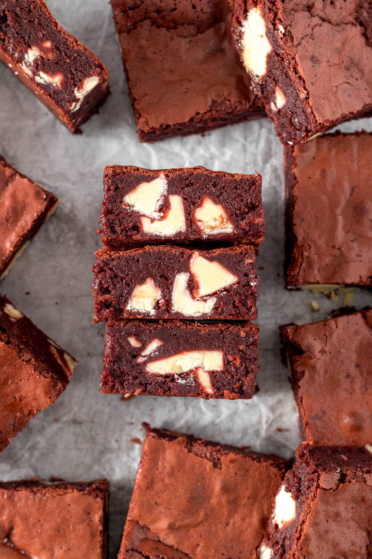 Three red velvet brownies on their sides showing white chocolate chunks.