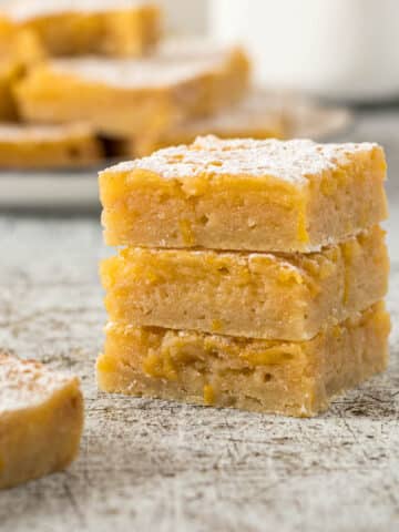 Three lemon bars stacked on each other with a dusting of icing sugar.