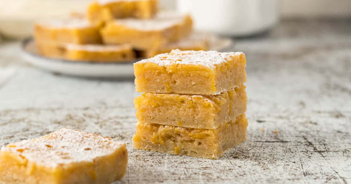 Three lemon bars stacked on each other with a dusting of icing sugar.