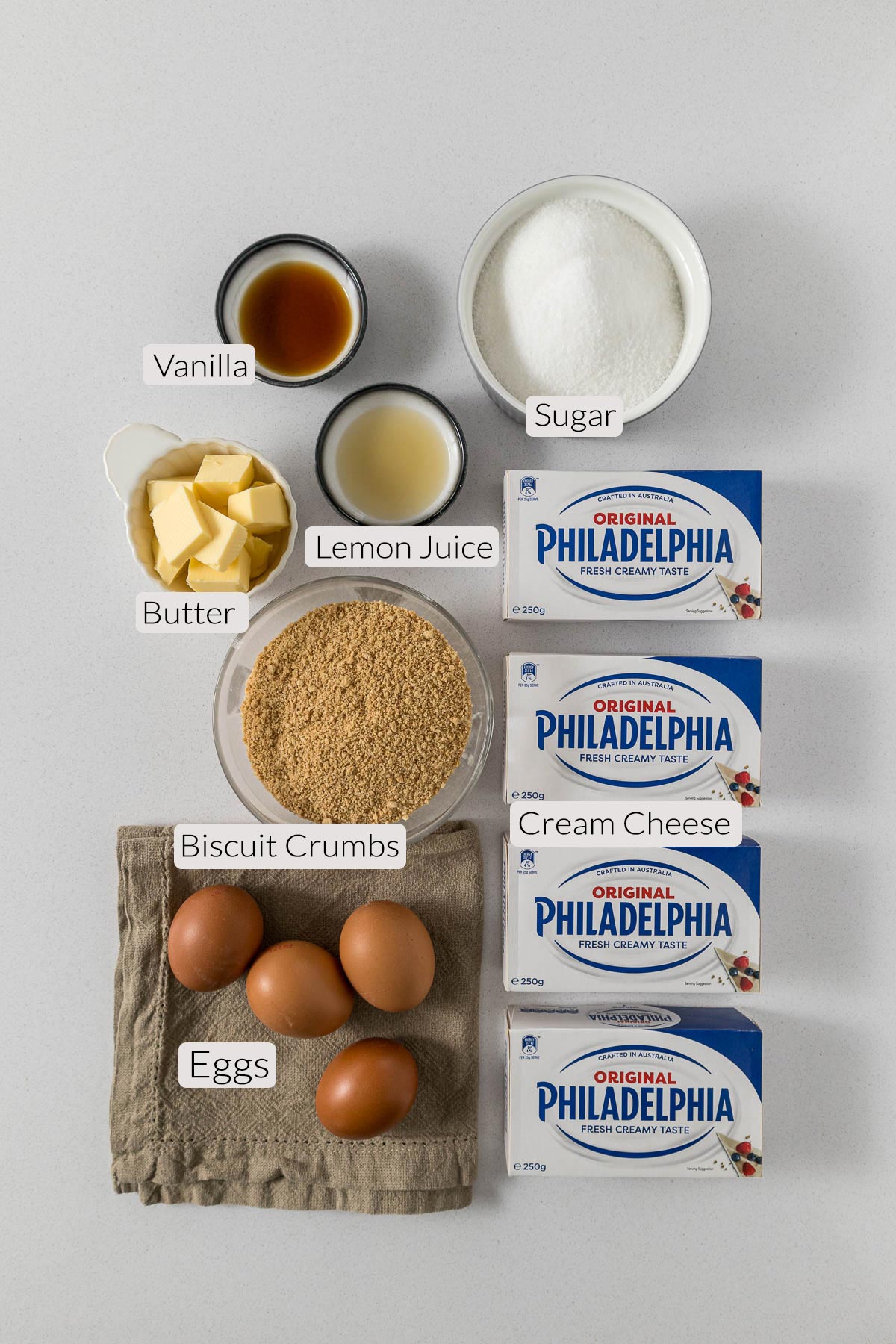 Philadelphia cheesecake ingredients - vanilla, lemon juice, sugar, biscuit crumbs, eggs, cream cheese.