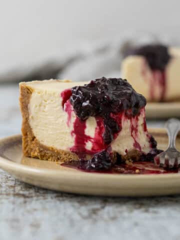 Slice of Philadelphia no-bake cheesecake on a plate with a berry compote.