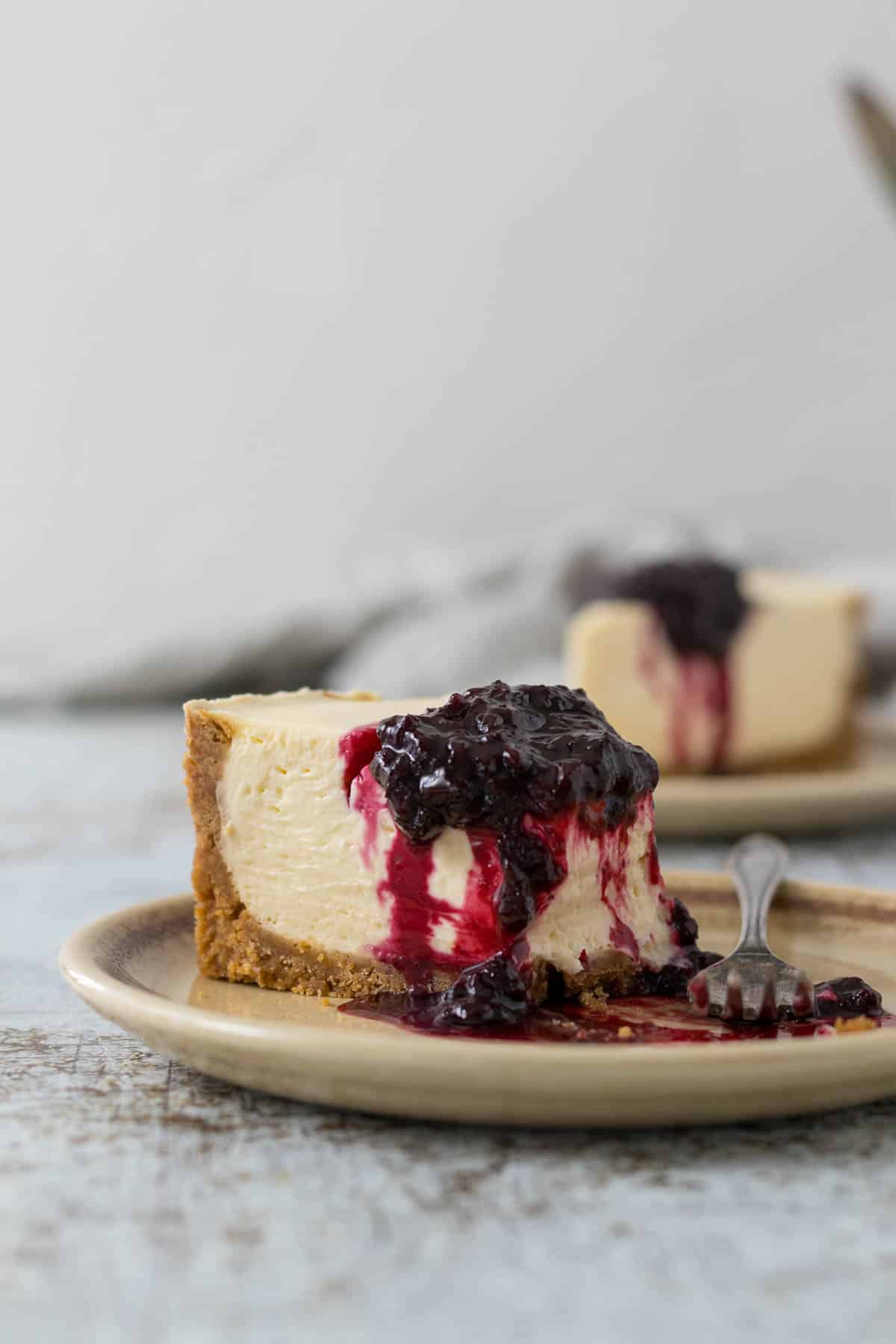 Slice of no-bake cheesecake on a plate with a berry compote.