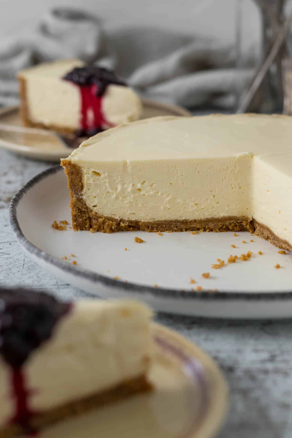 Sliced no bake cheesecake on a platter showing cross-section of biscuit base and creamy filling.