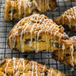 Chocolate chip scones with a vanilla glaze on a wired rack.