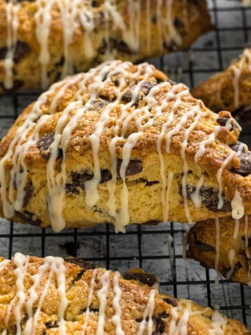 Chocolate chip scones with a vanilla glaze on a wired rack.