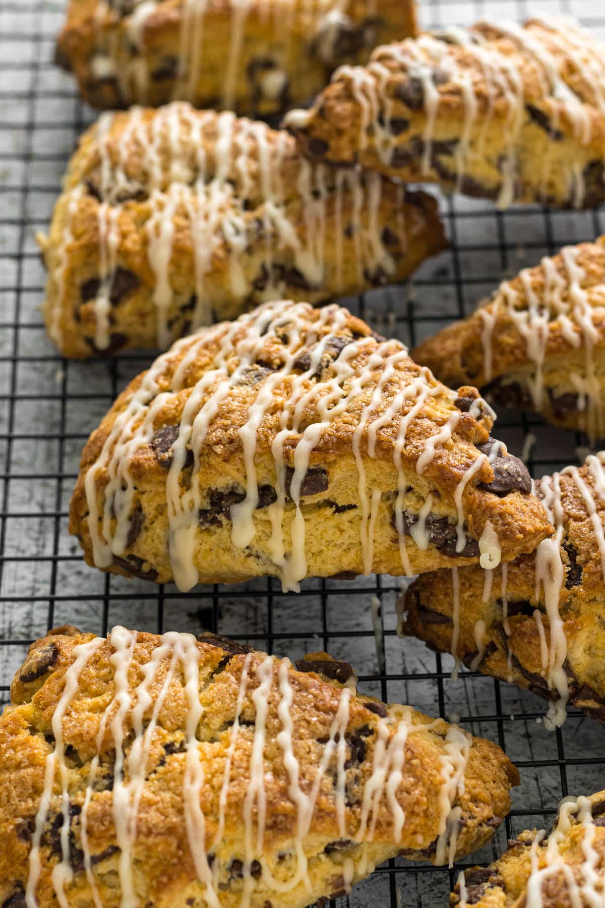 Chocolate chip scone with a vanilla glaze on a wired rack.