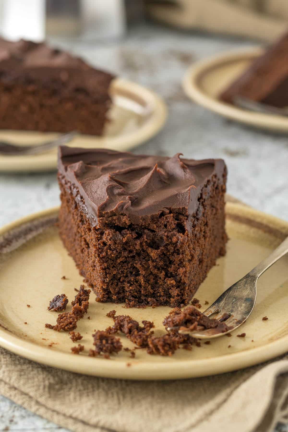 A slice of chocolate fudge cake on a plate with a cake fork.