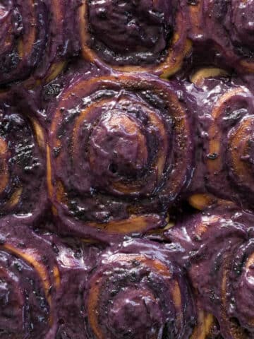 Blueberry cinnamon rolls with blueberry frosting in a baking dish.
