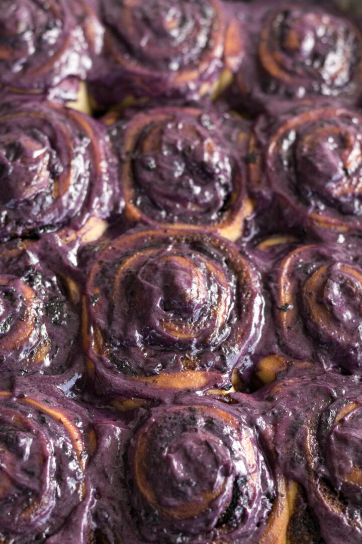 Blueberry cinnamon rolls topped with a blueberry cream cheese frosting.