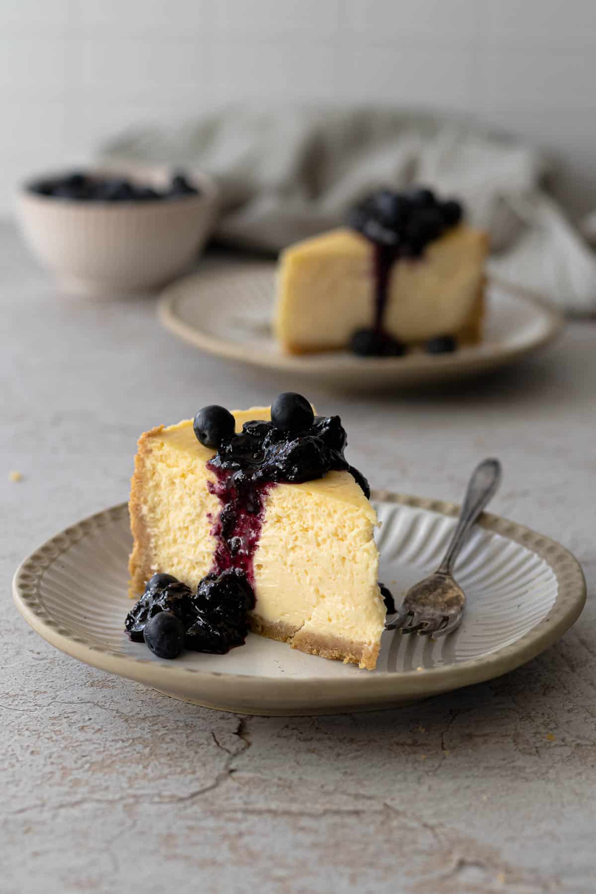 Slice of New York cheesecake with a blueberry sauce.