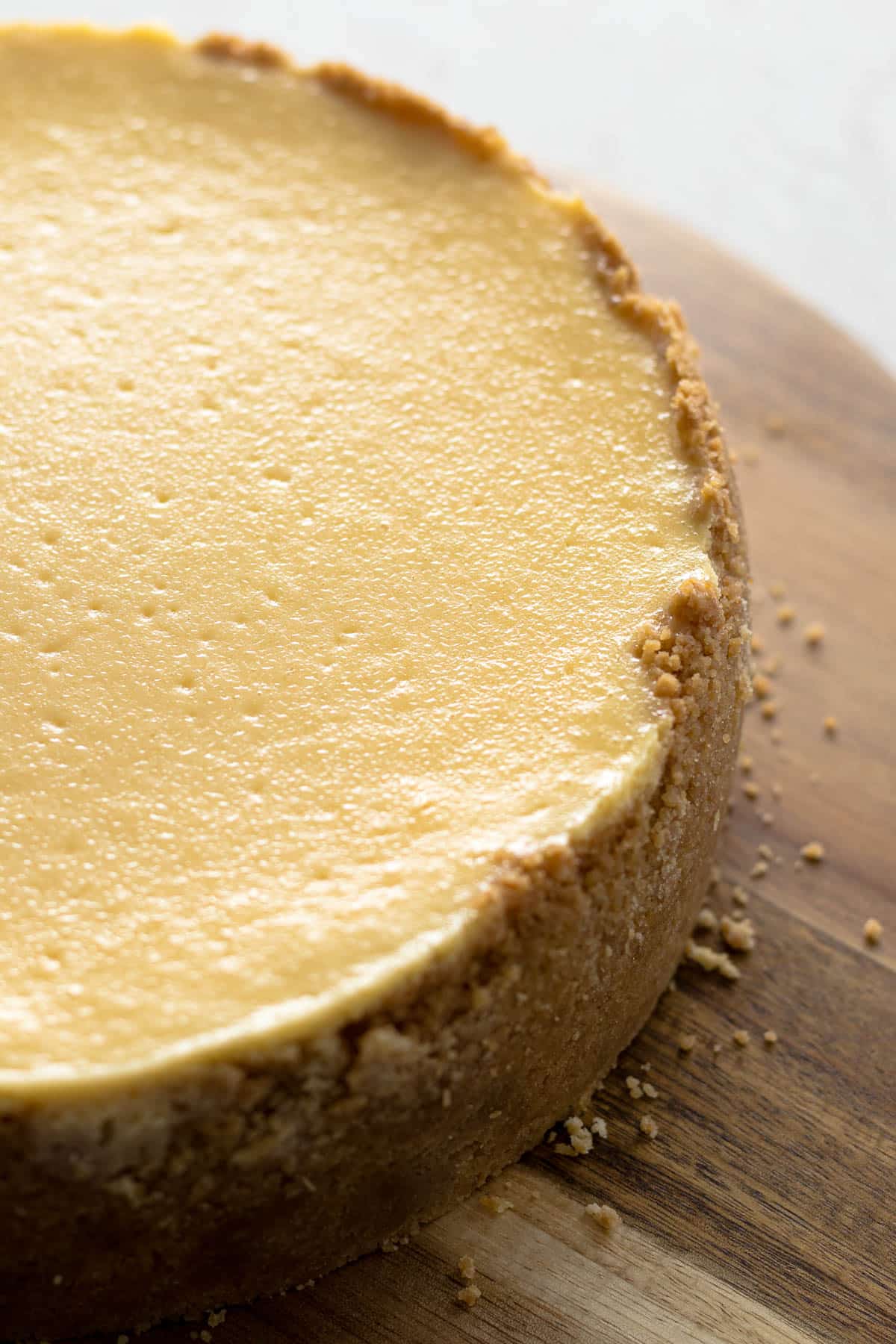 Unsliced New York cheesecake on a serving board.